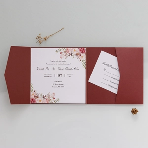 Flat lay of luxury burgundy tri-fold wedding invitation with floral card and RSVP details