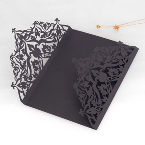 Detail of laser-cut black wedding invitation sleeve with intricate floral patterns