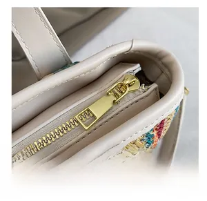 Détail de la fermeture éclair dorée sur un sac cabas en paille tissée avec bordure