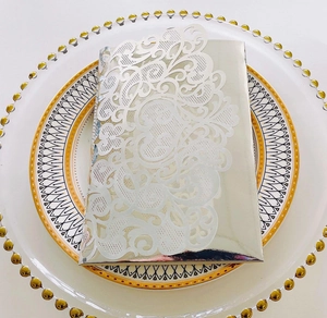 Close-up of laser-cut white floral wedding invitation with silver mirror paper detail