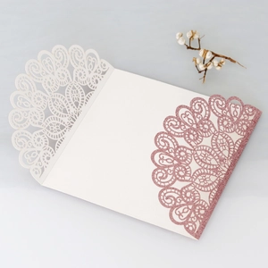 Detail of laser-cut peacock lace wedding invitation with rose gold glitter finish