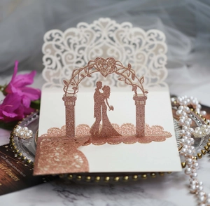 Detail of laser-cut wedding invitation featuring rose gold glitter heart and couple silhouette