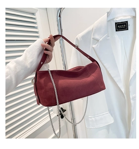 Detail of burgundy suede shoulder bag featuring silver chain and metal hardware