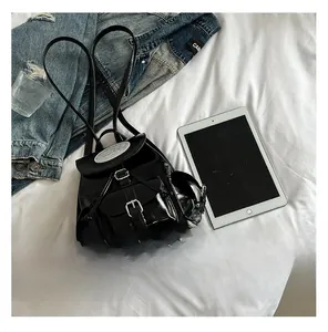 Détail d'un mini sac à dos en cuir verni noir avec rabat aimanté et poches latérales