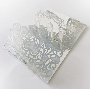 Macro view of 3D laser-cut silver wedding invitation with intricate vine patterns