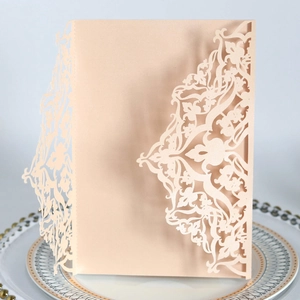 Close-up of laser-cut champagne wedding invitation with intricate floral details