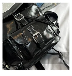Détail du sac à dos en cuir verni noir avec boucle métallique et cordon de serrage