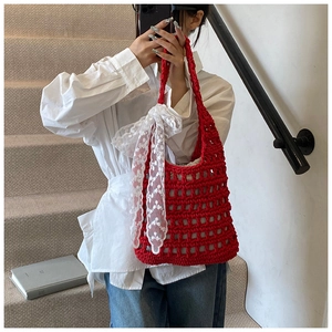 Detail of red hand-crocheted shoulder bag with white lace bow decoration and woven patterns