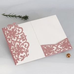 Dettaglio macro dell'invito glitter oro rosa tagliato al laser con motivi floreali
