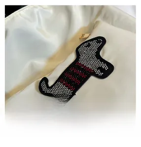 Close-up of sparkling rhinestone dachshund patch on a white nylon tote bag with metal zipper