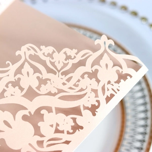 Macro shot of champagne laser-cut invitation sleeve with baroque hollowed pattern