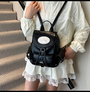 Vue latérale d'un mini sac à dos en cuir noir brillant avec écusson Moon Shark sur escalier