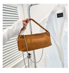 Detailed view of brown suede pillow bag featuring leather strap and silver metal chain