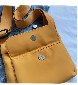 Dettaglio borsa a tracolla in nylon giallo con fibbia magnetica lucida e tracolla larga