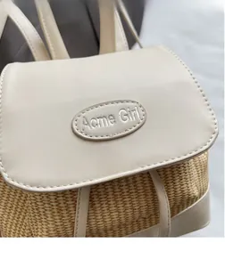 Detail der Acme Girl Stickerei auf cremefarbener Lederklappe und Stroh-Rucksack