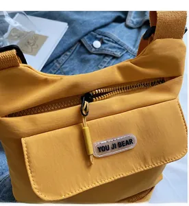 Dettaglio della borsa a tracolla in nylon giallo con cerniera e tessuto impermeabile
