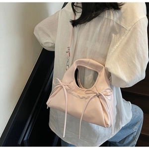 Détail d'un sac à main rose brillant avec des nœuds élégants et une poignée lisse