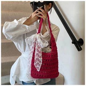 Detail of hand-woven magenta crochet bucket bag with lace bow and drawstring pouch