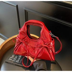 Détail d'un sac à main en cuir verni rouge avec nœuds décoratifs et ferrures argentées