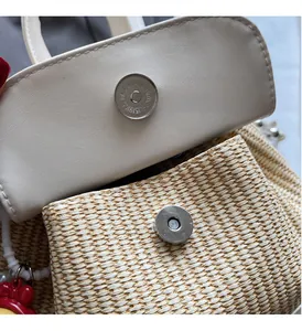 Detail der Strohhandtasche mit weißer Lederklappe und rundem Magnetverschluss aus Metall