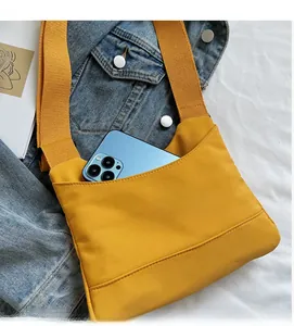 Dettaglio di una borsa a tracolla in tela gialla con tasca frontale per riporre lo smartphone