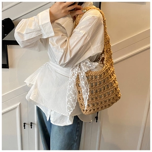 Macro shot of hand-woven crochet bucket bag featuring delicate lace ribbon bow detail