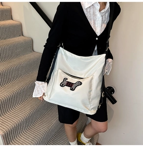 Detail view of white canvas crossbody bag featuring a cute dachshund embroidery and black strap