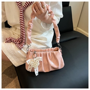 Detailed shot of pink pleated underarm bag featuring a pearl and lace bow charm