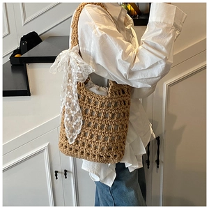 Detail of hand-woven beige shoulder bag with hollow mesh texture and large lace bow