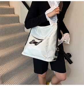 Detail of white nylon shoulder bag featuring cute dog embroidery and gold metal hardware