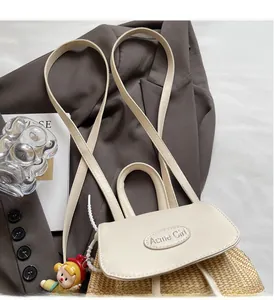 Detail der Acme Girl Stroh-Eimertasche mit weißer Lederklappe auf einem grauen Sakko