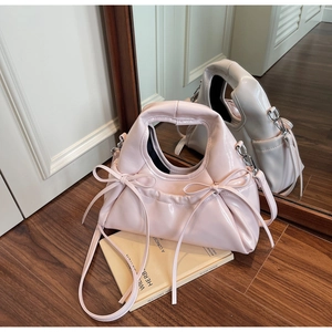 Détail d'un sac à main rose brillant avec design à volants et nœuds décoratifs