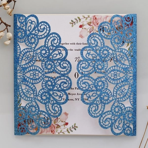 Macro detail of laser-cut glitter lace wedding invitation with floral insert and blue finish