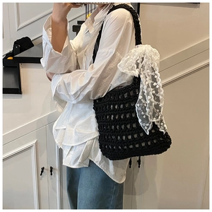 Detail view of black crochet woven shoulder bag with white lace floral bow decoration