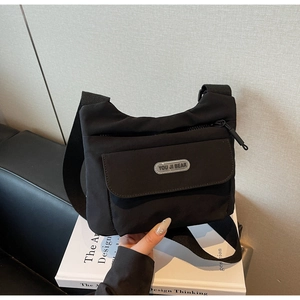 Dettaglio borsa a tracolla in nylon nero con tasca a patta e logo gommato del marchio incluso