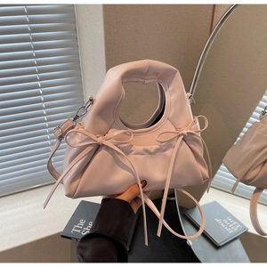 Détail du sac à bandoulière rose clair avec nœuds, texture froncée et boucles argentées