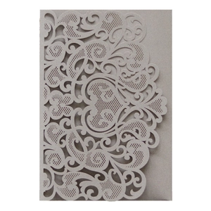 Macro detail of laser-cut wedding invitation featuring ornate heart patterns and lace edges