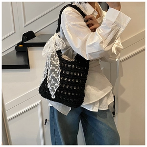 Detail of black woven shoulder bag featuring a large white lace bow and cotton lining