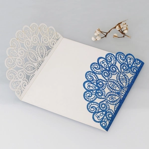 Close-up of laser-cut peacock lace pattern on blue glitter wedding invitation card