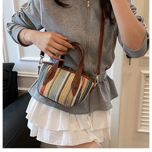 Détail du sac seau tissé coloré avec rayures et bandoulière en cuir marron élégant