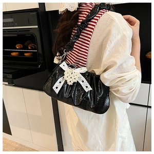 Détail du sac nuage noir brillant avec nœud en dentelle et pendentif cœur en perle
