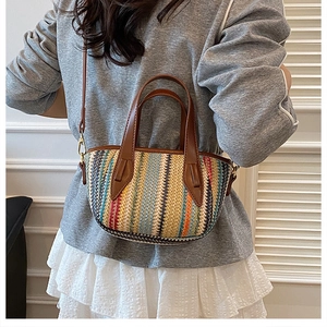 Détail d'un sac cabas en paille arc-en-ciel avec poignées et bandoulière en cuir brun