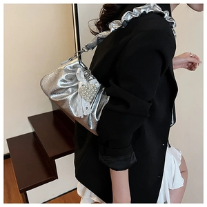 Détail du sac à main plissé argenté avec pendentif cœur en dentelle et bandoulière