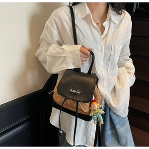 Detailansicht des Rucksacks aus Leder und Stroh mit Acme Girl-Logo und Anhänger