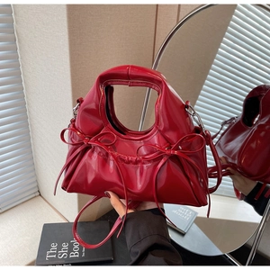 Détail du sac à main en cuir verni rouge avec nœuds et texture plissée élégante