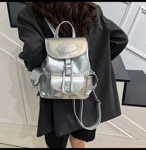 Détail du sac à dos métallique argenté avec fermeture à rabat et gaufrage circulaire