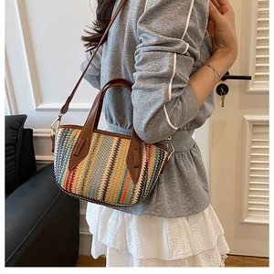 Détail d'un sac seau tissé à rayures colorées avec poignées en cuir marron et boucles dorées