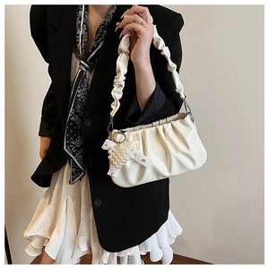 Detail of off-white pleated shoulder bag with pearl heart charm and bow accessory