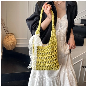 Close-up of lime yellow crochet bucket bag with hollow knit and white lace bow detail