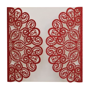 Close-up of laser cut red glitter wedding invitation with intricate floral lace pattern